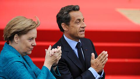 Die Kanzlerin und der Gastgeber: Angela Merkel und Nicolas Sarkozy grüßen in die Menge.