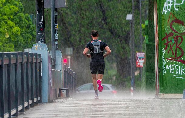 Ein Mann joggt bei strömendem Regen.