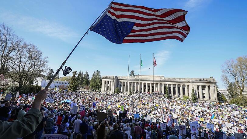 Lee Telnack schwenkt eine umgedrehte amerikanische Flagge an einer Angelrute während einer "Remove, Reverse, Reclaim"- und "Hands Off!"-Demonstration vor dem State Capitol in Olympia, Washington.