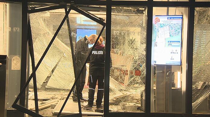 Ermittler stehen nach der Sprengung eines Geldautomaten im verwüsteten Vorraum einer Bank.