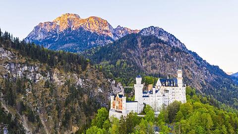 Hinter Neuschwanstein strahlt der Säuling im Morgenlicht.