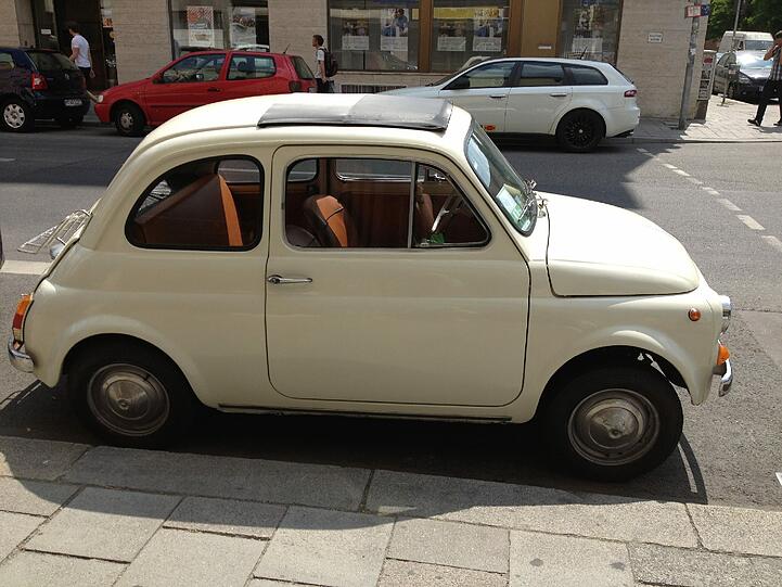 Auch ohne Koffer auf dem Heck ein echter Hingucker: Ein kleiner creme-farbener Fiat 500 in der Theresienstraße.