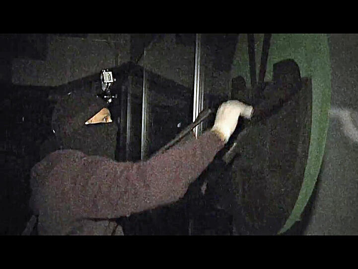 Mit spezieller abwaschbarer Sprühkreide bringt der Mann mit der Sturmhaube und der Stirnlampe das schwarz-gelbe Logo der Dortmunder am Fenster an.