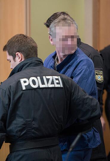 Der Angeklagte Rudolf R. wird am 21.02.2013 in Augsburg von mehreren Polizisten in den Sitzungssaal geführt.