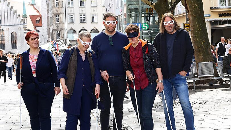 Stefanie Freitag (v.l.n.r.), Leitung Bezirksgruppe München des BBSB, sowie die Stadträte Sofie Langmeier, Stefan Jagel, Barbara Likus und Roland Hefter mit Simulationsbrillen, Schlafmaske und Blindenstock beim Selbstversuch in der Fußgängerzone.