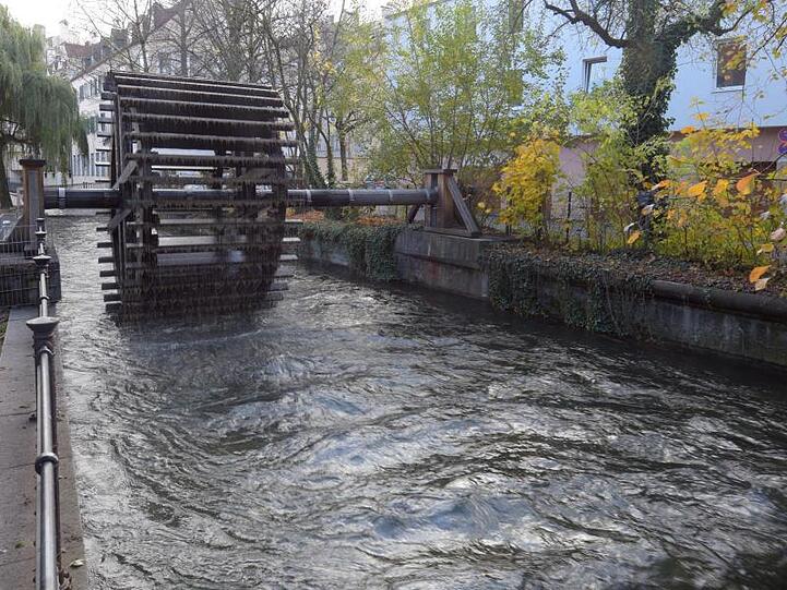 Ein Wasserrad dreht sich an einem Stadtkanal in Augsburg. Foto: Stefan Puchner/Archivbild