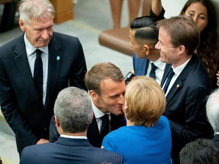 Angela Merkel wird am Rande des UN-Klimagipfels von Emmanuel Macron und Harrison Ford (l) begrüßt.