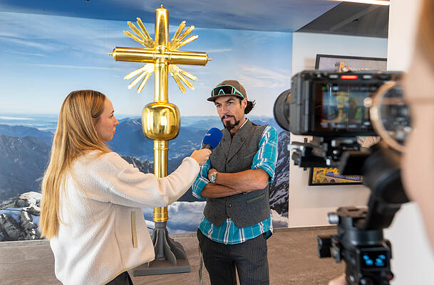 Der Künstler Bernhard Rieger hat das neue Gipfelkreuz geschaffen. Hier wird am Vormittag vor seinem Kunstwerk auf der Zugspitze interviewt.