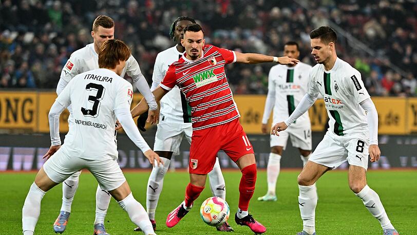 Der Augsburger Mergim Berisha (M) kämpft mit Ko Itakura (l) und Julian Weigl (r) von Mönchengladbach um den Ball.