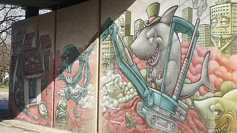 Ein fies grinsender Miethai, dessen Bagger das Uhrmacherhäusl auffrisst &ndash; im Hintergrund traurig dreinschauende Hochhäuser. Dieses Graffiti am Kolumbusplatz zeigt, wie groß die Wut der Obergiesinger ist über das, was in ihrem Viertel passiert ist.