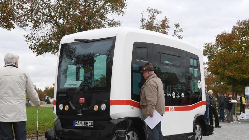 Zwei Männer betrachten einen autonom fahrenden Minibus auf einer Straße in Bad Birnbach. Zwei Männer betrachten einen autonom fahrenden Minibus auf einer Straße in Bad Birnbach.