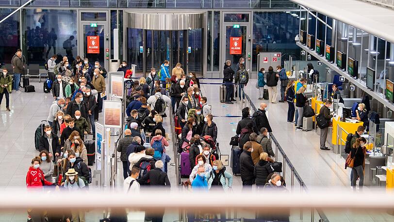 Passagiere stehen am Flughafen München an einem Check-In-Schalter. Passagiere stehen am Flughafen München an einem Check-In-Schalter.