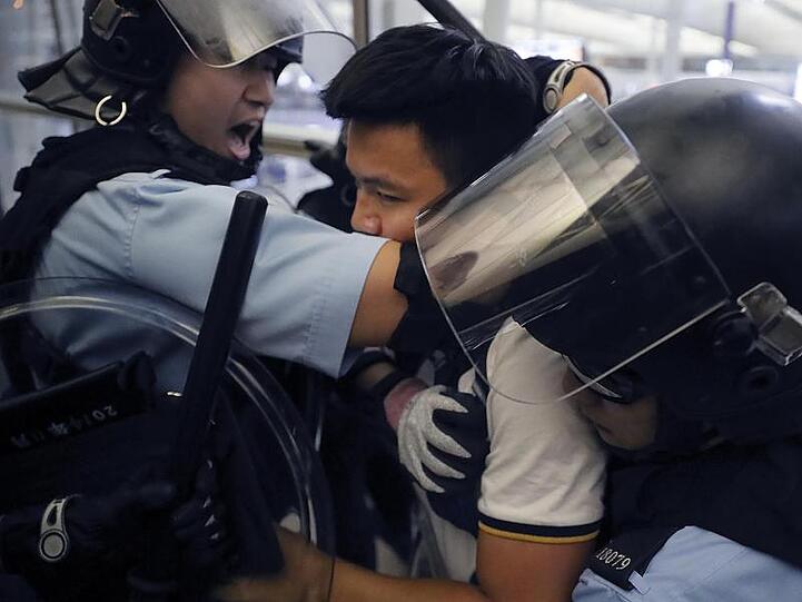 Polizisten in Schutzausrüstung nehmen einen Demonstranten im Hongkonger Flughafen fest. Kin Cheung/AP