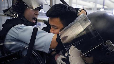 Polizisten in Schutzausrüstung nehmen einen Demonstranten im Hongkonger Flughafen fest. Kin Cheung/AP