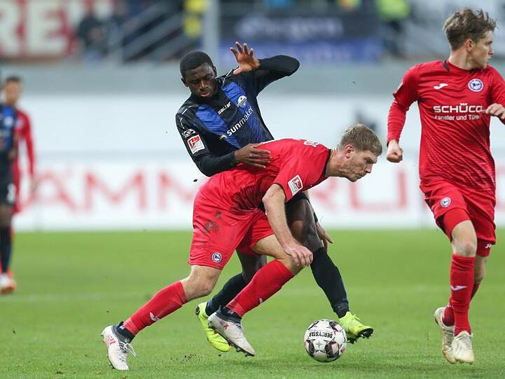 Paderborns Jamilu Collins (l) versucht Arminia-Torjäger Fabian Klos (M) zu stoppen.