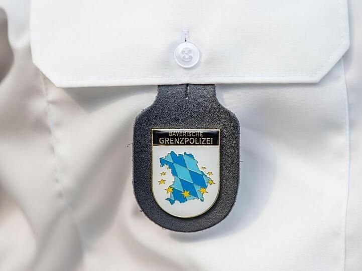 Das Emblem der bayerischen Grenzpolizei hängt am Hemd eines Polizeibeamten. Foto: Lino Mirgeler/Archivbild