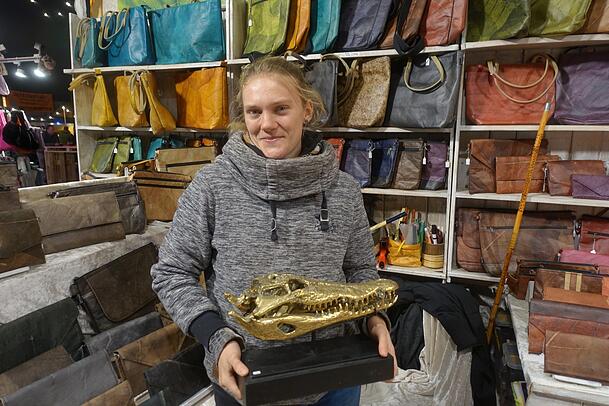Marlena Frisch mit einem Krokodilkopf vor ihren Taschen aus Teakblättern.