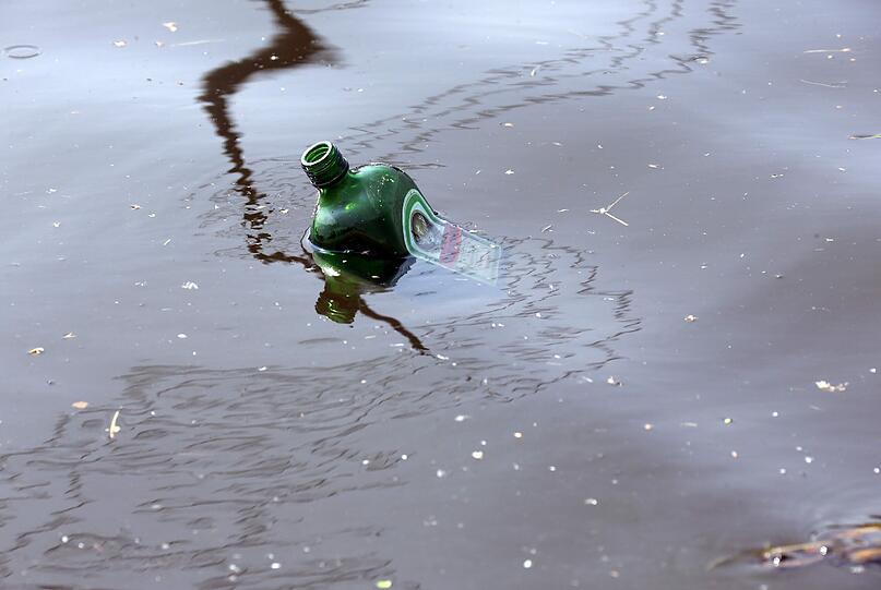 Eine Glasflasche schwimmt in der Elbe.