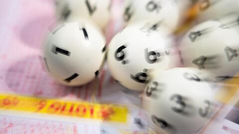 Lotto-Kugeln liegen auf einem Lottoschein. Foto: Tom Weller/dpa/Illustration