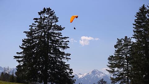 Ein Gleitschirmflieger gleitet am Buchenberg im Allgäu über eine Bergwiese. (Archivbild)
