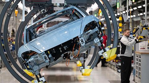 Ein Mitarbeiter der Porsche AG montiert in einer Produktionshalle des Stammwerks einen Porsche Taycan.