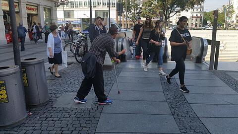 Erst stützt sich der Mann am Stachus auf die Krücke und bettelt um Geld...