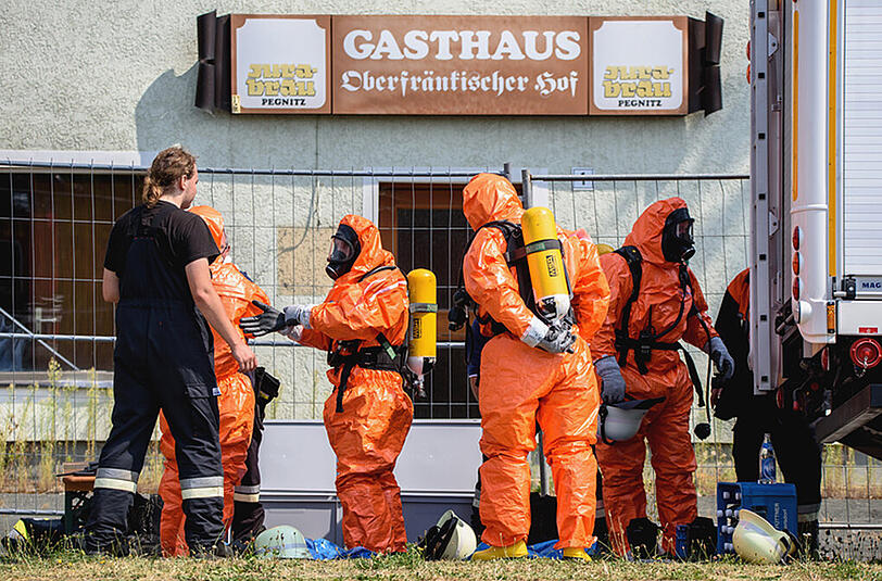 Untersuchung des Absturzortes: Einsatzkräfte der Feuerwehr ziehen sich am 11.08.2015 in Engelmannsreuth Ganzkörper-Schutzanzüge an.