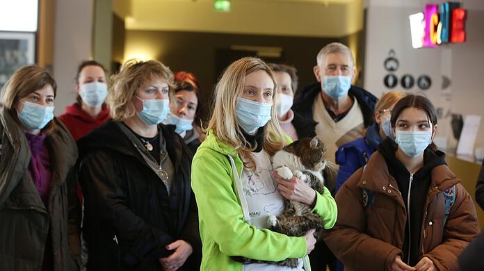 Sogar die Katze hat die Flucht nach München geschafft. Kurz nach der Ankunft im Reisebus sammeln sich die erschöpften Frauen in der Lobby.