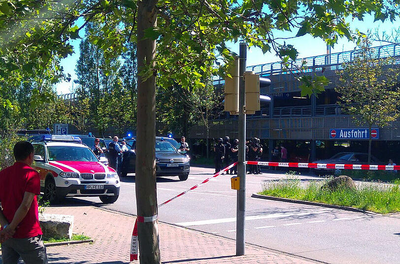 Passanten und Einsatzkräfte der Polizei stehen in Viernheim (Hessen) in der Nähe eines Kinos, in dem sich ein bewaffneter Mann verschanzt hat.