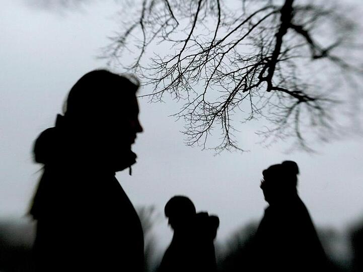 Passanten stehen neben einem Baum. Foto: Julian Stratenschulte/dpa/Archivbild