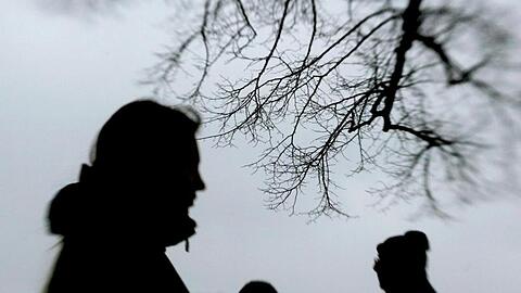 Passanten stehen neben einem Baum. Foto: Julian Stratenschulte/dpa/Archivbild