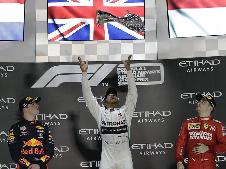 Sieger Lewis Hamilton (M) wirft den Pokal zwischen Max Verstappen (l) und Charles Leclerc in die Höhe.