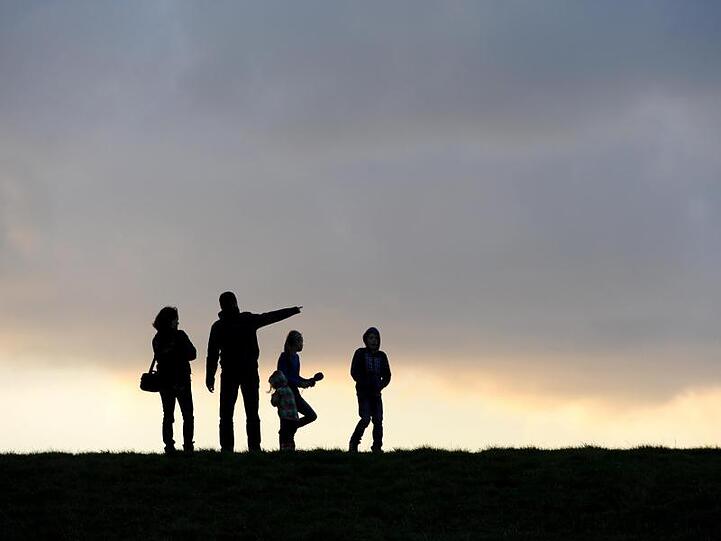 Eine Familie beim Spaziergang unterm abendlichen Wolkenhimmel.