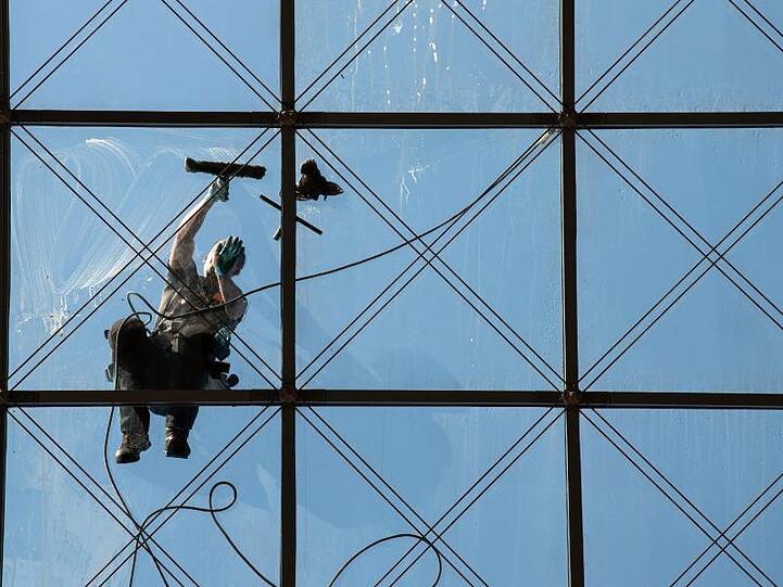 Ein spezialisierter Glas- und Gebäudereiniger putzt in 27 Metern Höhe ein Dach.