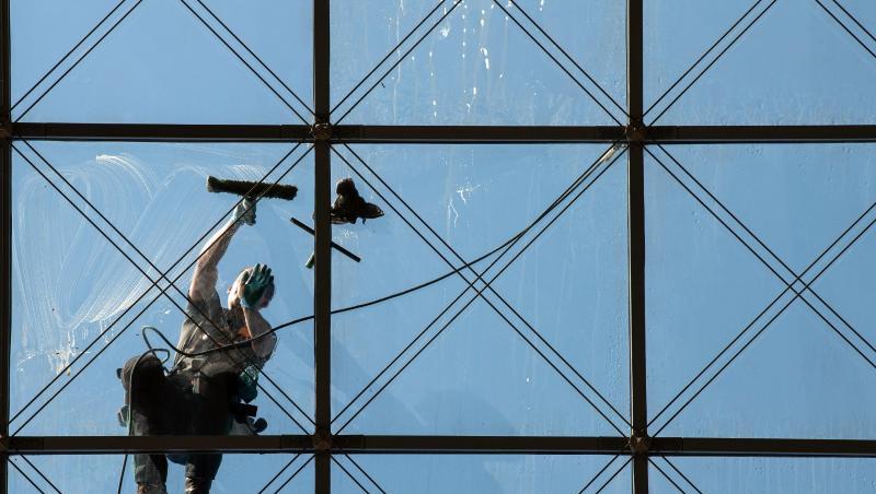 Ein spezialisierter Glas- und Gebäudereiniger putzt in 27 Metern Höhe ein Dach. Ein spezialisierter Glas- und Gebäudereiniger putzt in 27 Metern Höhe ein Dach.