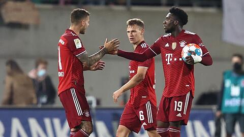 Alphonso Davies (r) klatscht nach dem Sieg mit Lucas Hernández (l) ab. Daneben steht Joshua Kimmich.