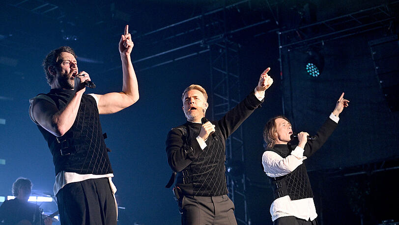 Take That live auf der Bühne am 02.07.2024 in München, Olympiapark. Tollwood-Festival.
Das Bild zeigt von rechts. Sänger Mark Owen,  Sänger  Gary Barlow und Sänger Howard Donald.
