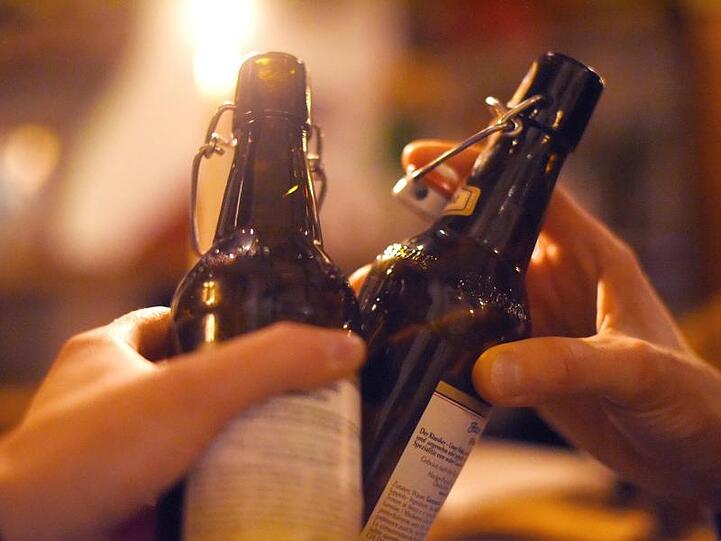 Zwei Personen stoßen in einer Kneipe mit Bier an. Foto: Angelika Warmuth/dpa/Symbolbild