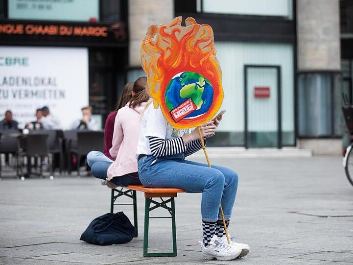 Eine Schülerin mit einem selbstgemachten Plakat vor dem Kölner Hauptbahnhof.