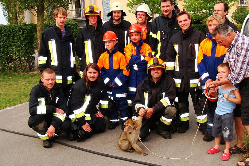 An der Leine: Berberaffen-Dame Minna mit ihrem Trainer (r.) und Feuerwehrleuten aus Altmühldorf.