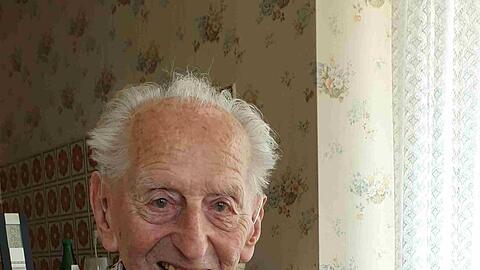 Karl Haidle sitzt an seinem 104. Geburtstag an einem Tisch und liest Zeitung.