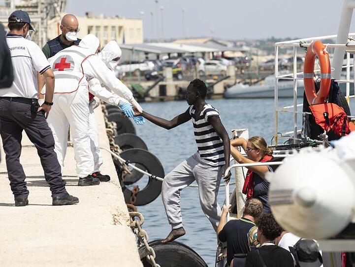 Migranten verlassen im Hafen von Pozzallo auf Sizilien ein Rettungsschiff.