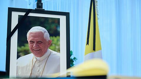 Das Kondolenzbuch für den verstorbenen emeritierten Papst Benedikt XVI.liegt auf einem Tisch vor einem Bild des Verstorbenen.