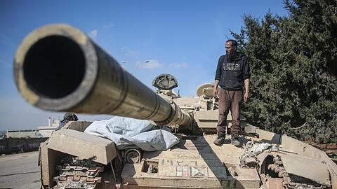 Ein Kämpfer der Nationalen Befreiungsfront (NFL) steht auf einem zurückgelassenen Panzer der syrischen Regierungstruppen.