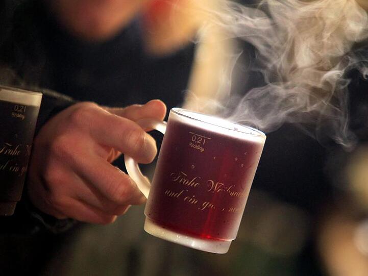 Eine Tasse mit Glühwein wird gehalten. Foto: Karl-Josef Hildenbrand/dpa/Archivbild