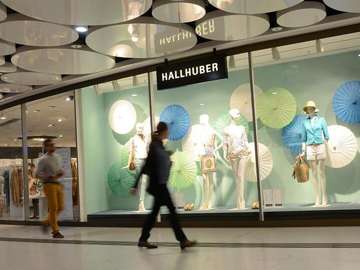 Eine Frau geht in Münche an einem Schaufenster des Modehauses Hallhuber vorbei. Foto: Tobias Hase/Archiv