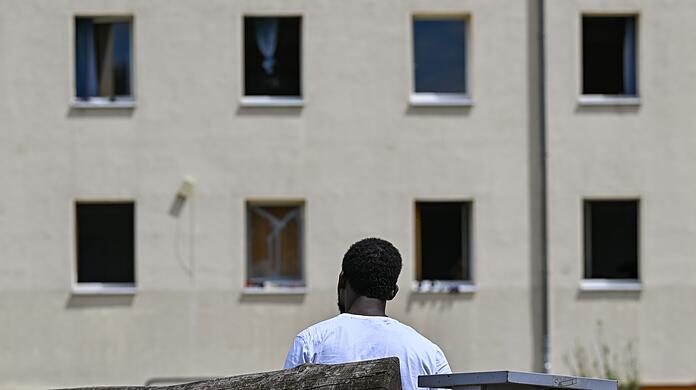 Ein Migrant sitzt auf einer Bank auf dem Gelände der Zentralen Erstaufnahmeeinrichtung für Asylbewerber des Landes Brandenburg in Eisenhüttenstadt. (Archivfoto)