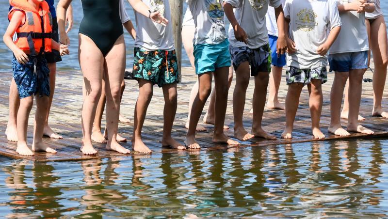Jungen und Mädchen stehen in einer Ferienanlage auf einer Badeinsel.