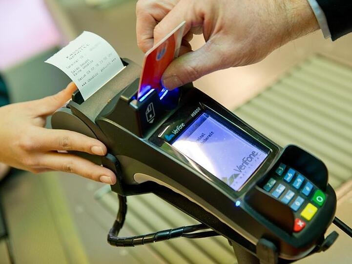 Ein Kunde zahlt in einem Supermarkt mit einer EC-Karte an der Kasse. Die Corona-Krise hat dem Bezahlen per Karte Studien zufolge einen Schub gegeben.