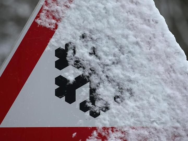 Schneebedeckt ist ein Warnschild das auf Schneeglätte hinweist. Foto: Karl-Josef Hildenbrand/dpa/Archivbild